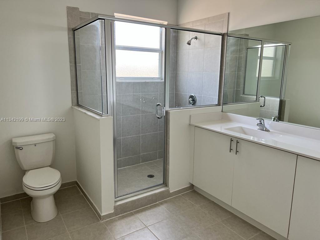 2633 Southeast 10th Street, Unit 2633 Homestead, FL 33035 - Photo 15 of 42 a bathroom with a granite countertop sink a toilet and a mirror