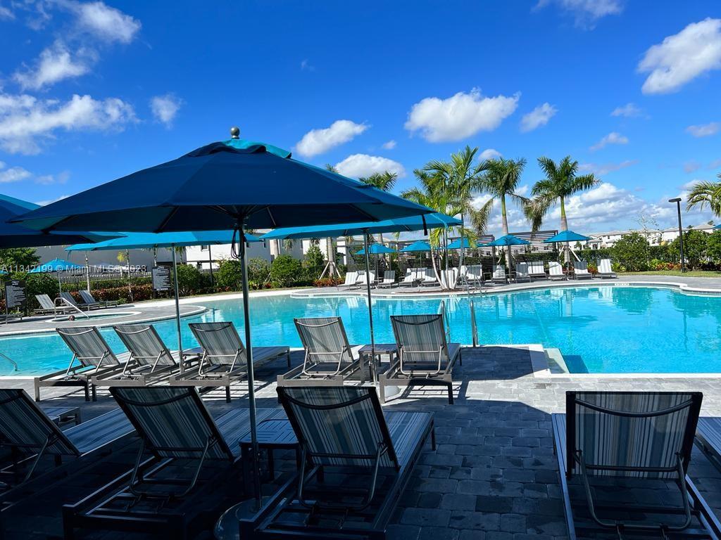 2633 Southeast 10th Street, Unit 2633 Homestead, FL 33035 - Photo 40 of 42 a view of a patio with table and chairs under an umbrella with a lake view