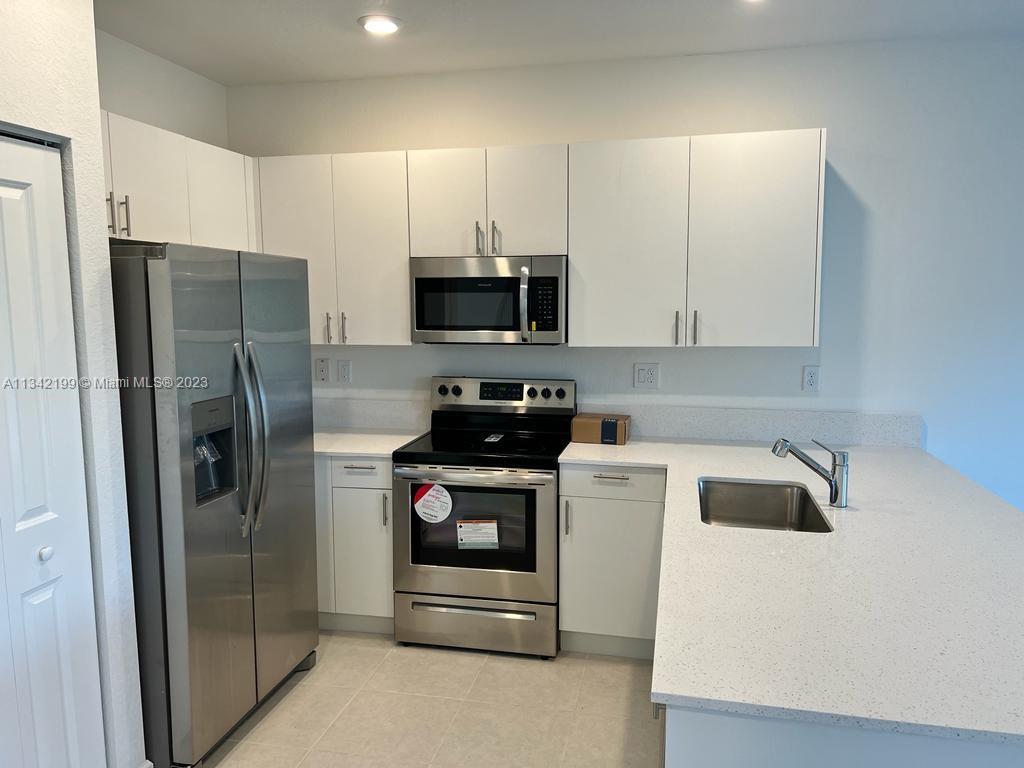 2633 Southeast 10th Street, Unit 2633 Homestead, FL 33035 - Photo 8 of 42 a kitchen with a refrigerator sink and stove