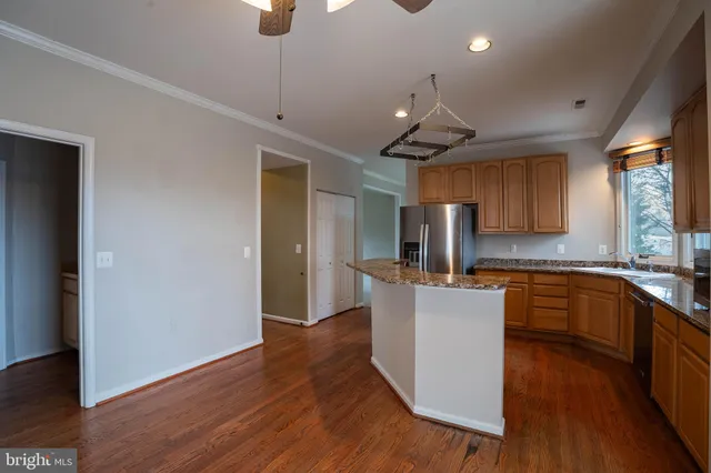a kitchen with kitchen island stainless steel appliances a sink cabinets and wooden floor