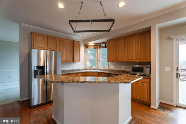 a kitchen with stainless steel appliances granite countertop a sink a refrigerator a stove a microwave and island