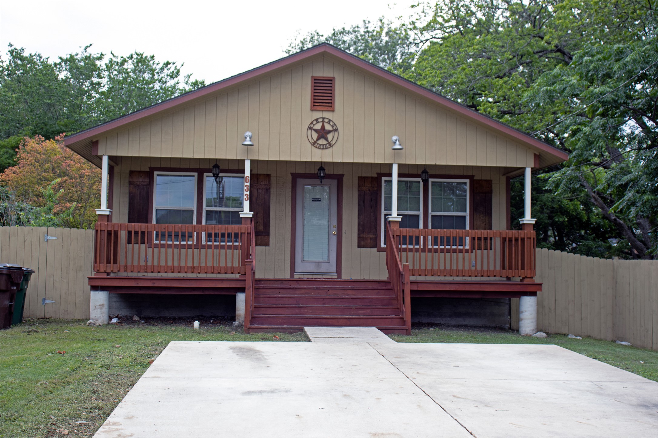 Single-story residence featuring light-toned horizontal siding, a covered front porch with painted wood railings, and a gabled roofline