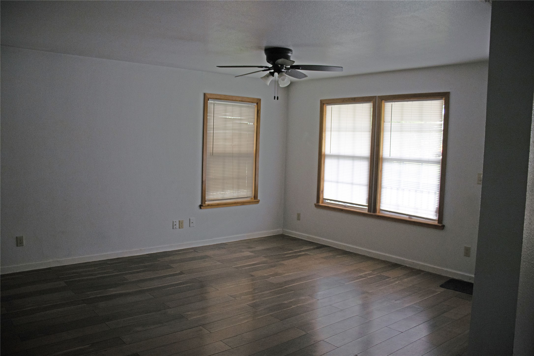 633 South Commerce Street Lockhart, TX 78644 - Photo 11 of 29 Spacious room featuring wood-finish flooring, white walls, and a ceiling fan