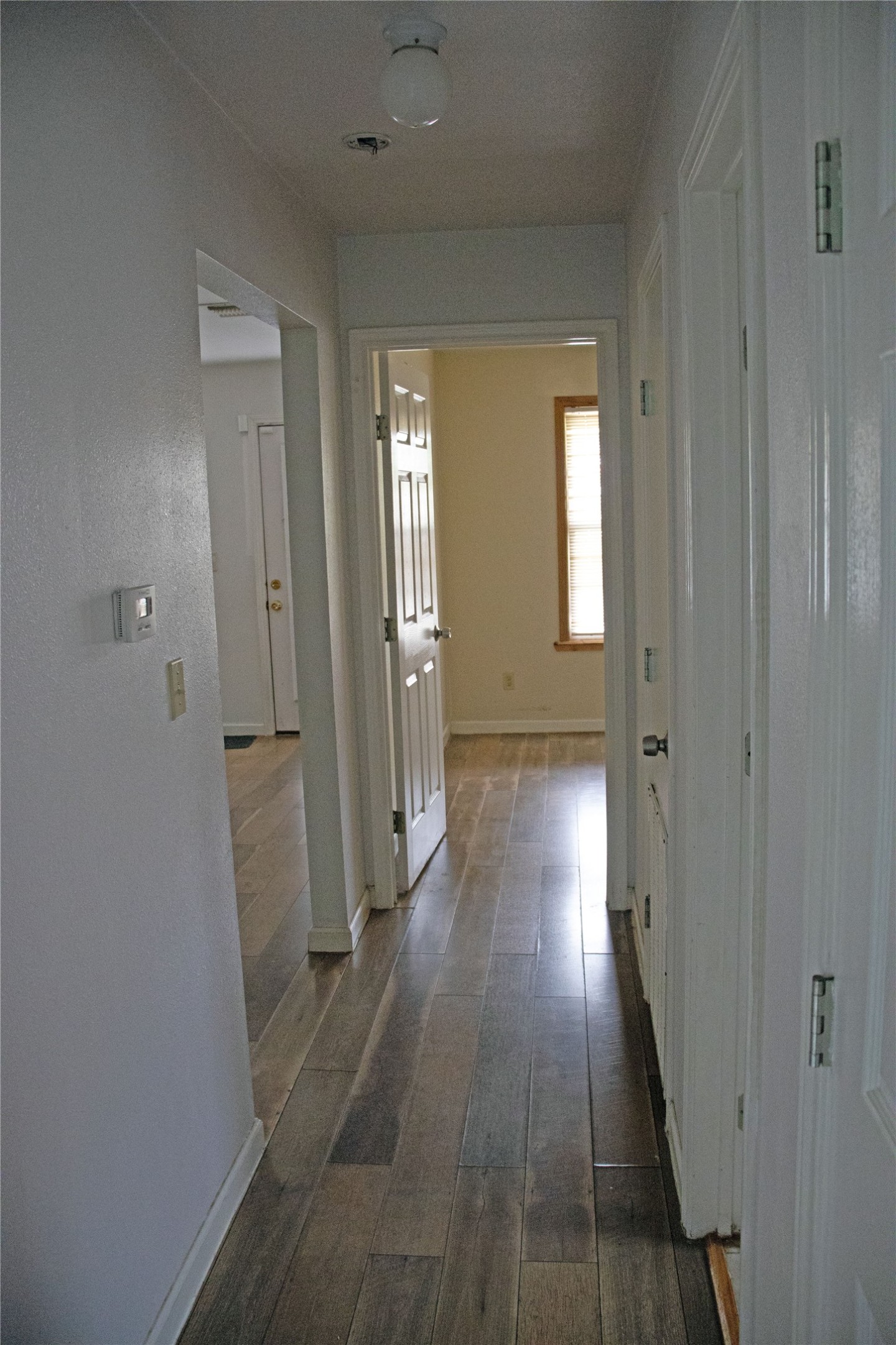 633 South Commerce Street Lockhart, TX 78644 - Photo 16 of 29 Hallway featuring wood-look plank flooring, white baseboards, and multiple doorways with panel doors