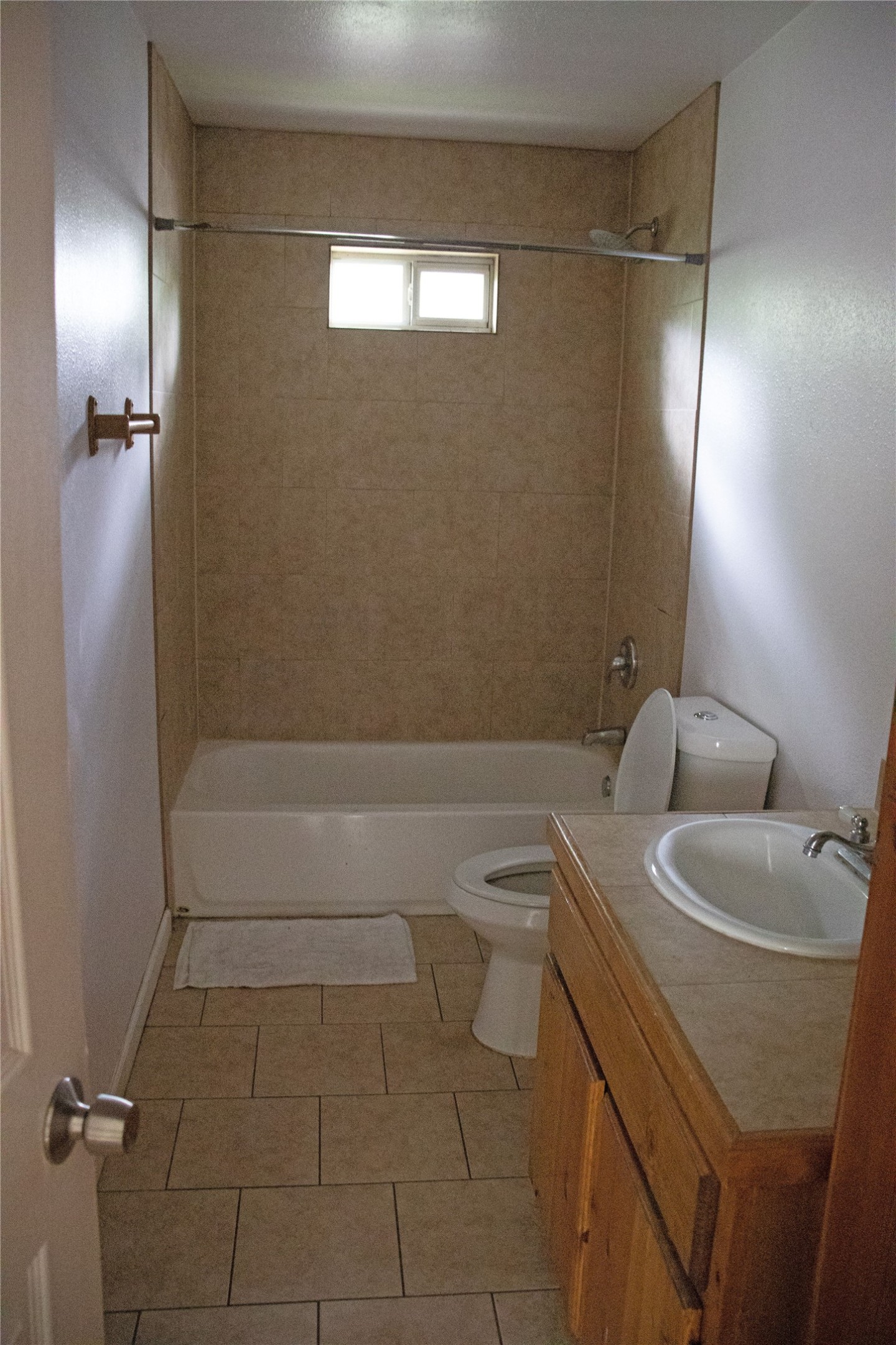 633 South Commerce Street Lockhart, TX 78644 - Photo 17 of 29 Bathroom featuring a tub/shower combination with tile surround, a single vanity with wood-finish cabinetry, a white basin sink, and tile flooring