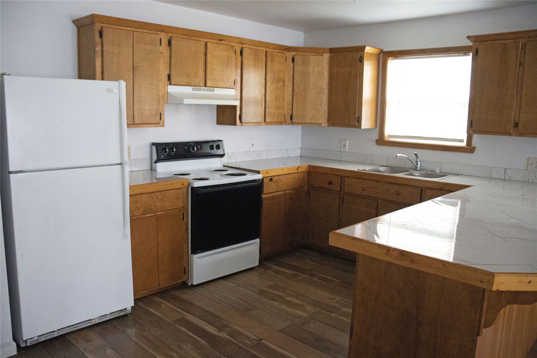 633 South Commerce Street Lockhart, TX 78644 - Photo 2 of 29 Kitchen featuring wood-finish flooring, a double basin sink, light-toned cabinetry, and white appliances