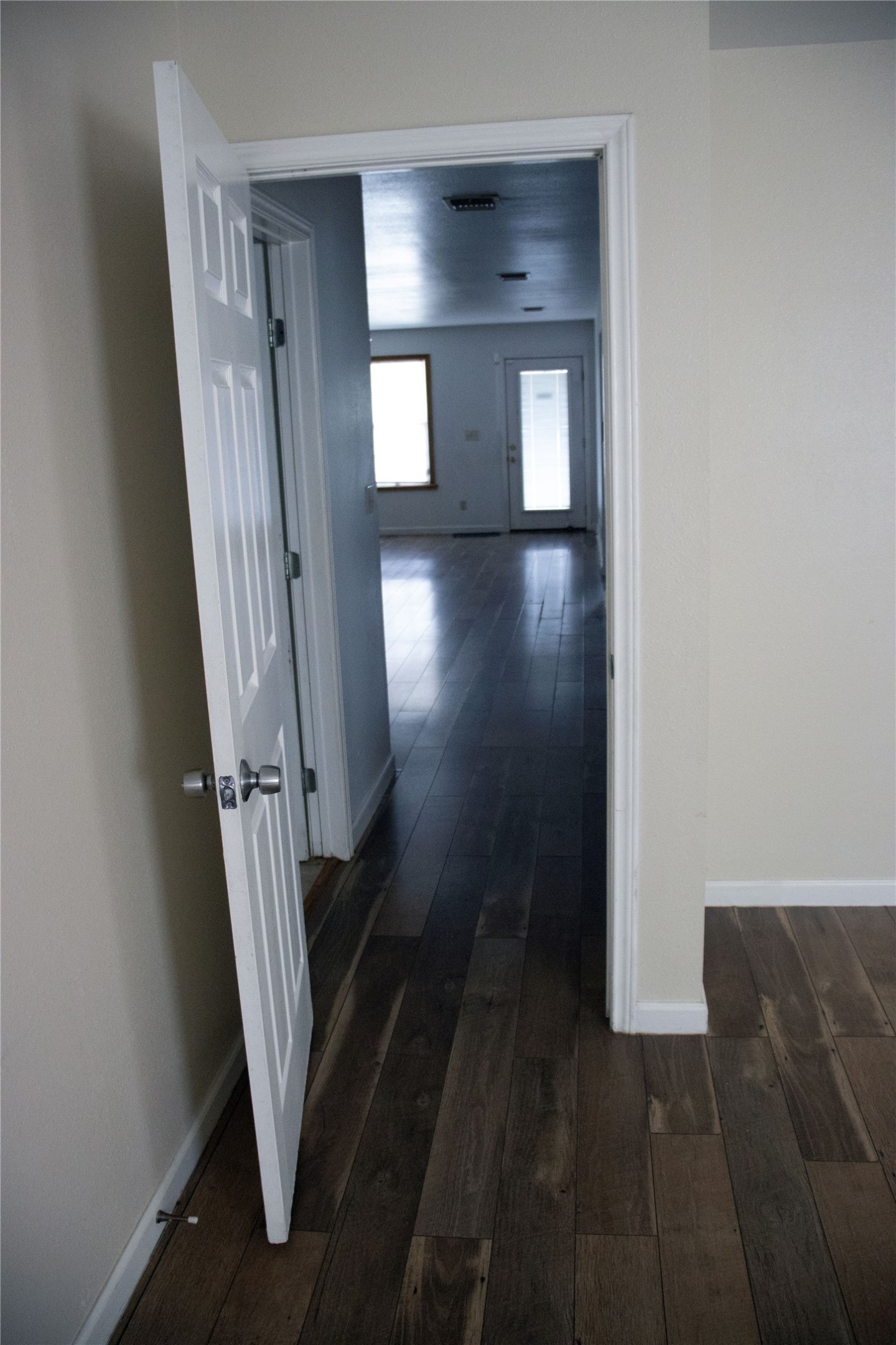633 South Commerce Street Lockhart, TX 78644 - Photo 22 of 29 Wood-finish plank flooring extends through a doorway into a sunlit interior space, featuring a window and a glass-paneled door