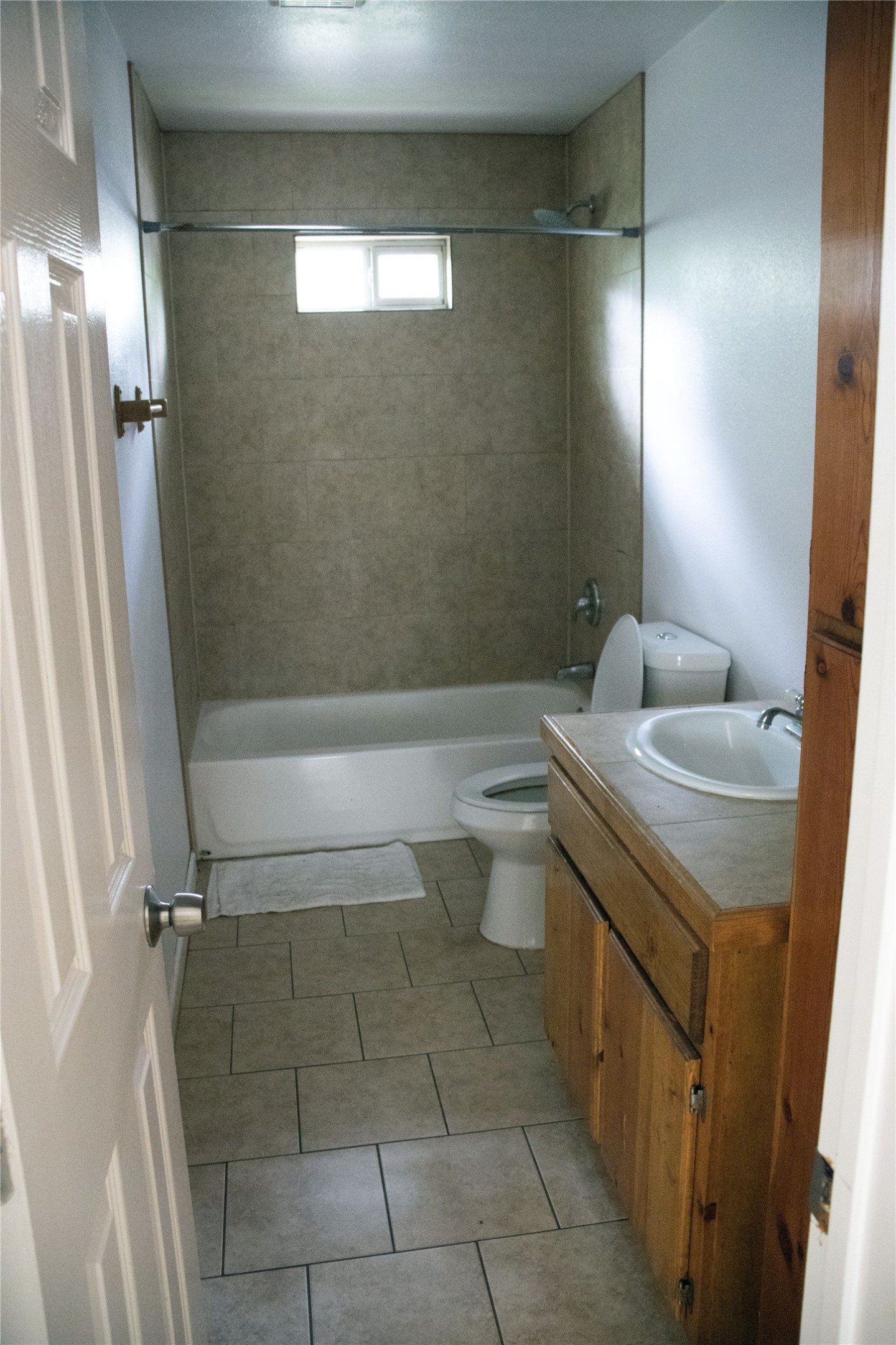 633 South Commerce Street Lockhart, TX 78644 - Photo 23 of 29 Full bathroom featuring a tub-shower combination with tiled surround, a window in the shower, and a light wood-finish vanity with an integrated sink