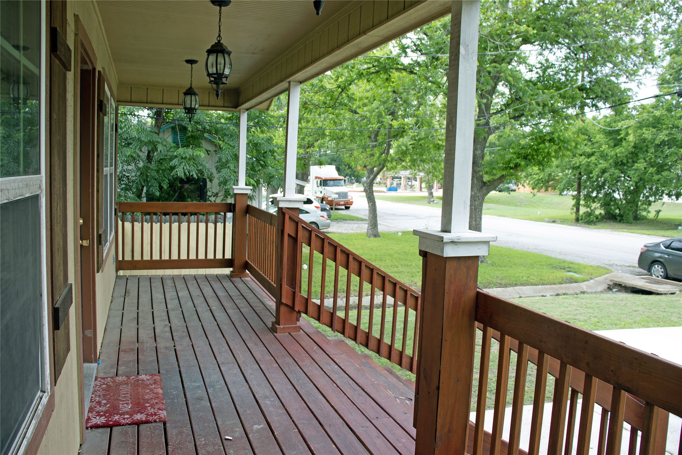 633 South Commerce Street Lockhart, TX 78644 - Photo 4 of 29 Covered front porch featuring wood-finish flooring, wood railings, and two hanging porch lights