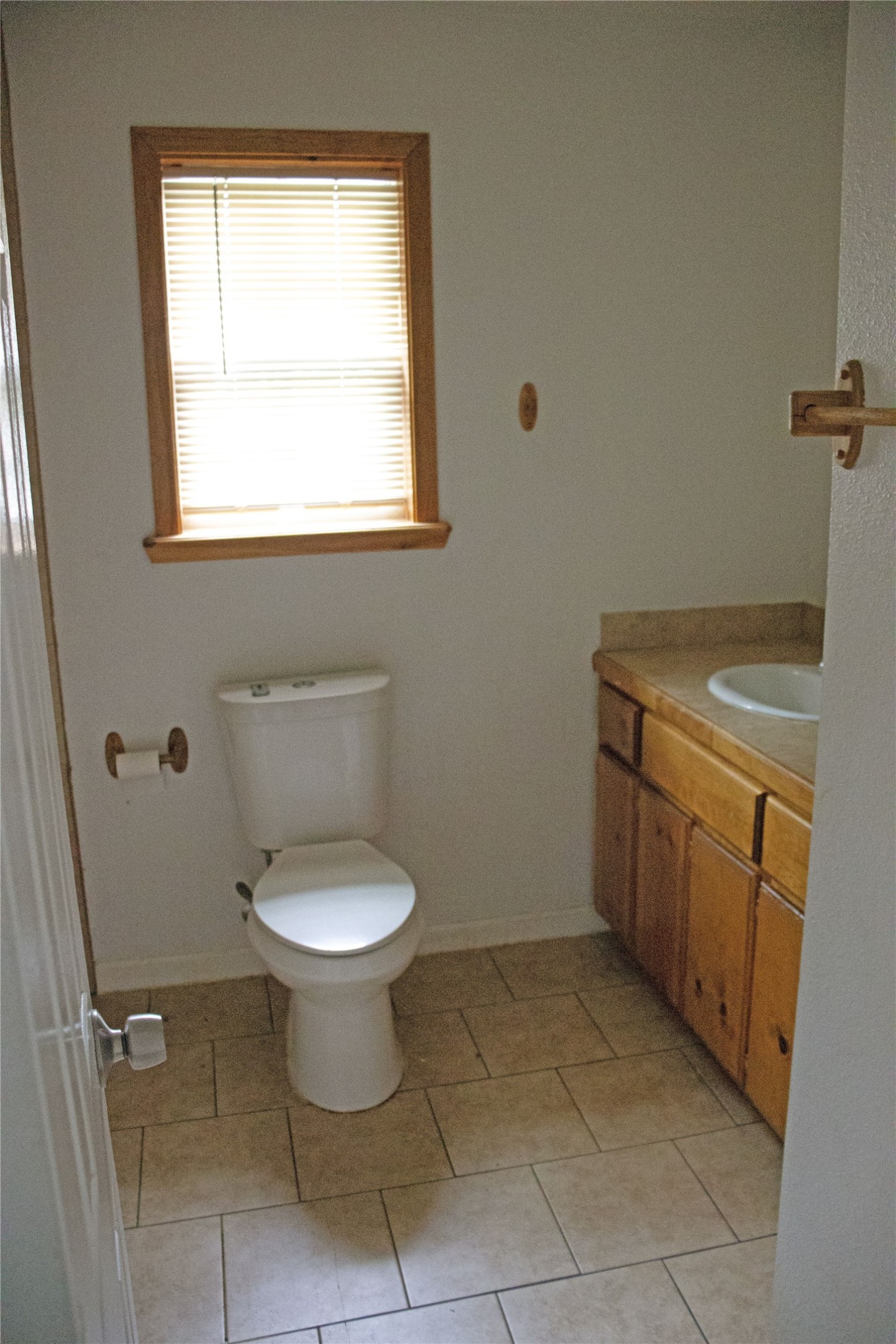 633 South Commerce Street Lockhart, TX 78644 - Photo 8 of 29 Bathroom featuring a single-pane window with wood-finish trim, a porcelain toilet, a wood-finish vanity with a drop-in sink, and tile flooring
