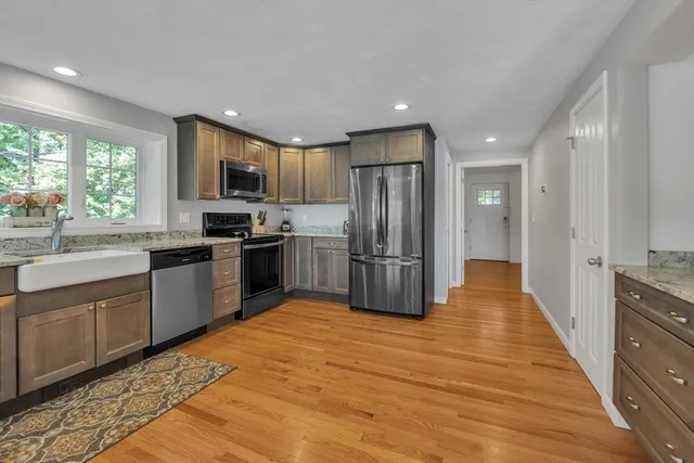 a large kitchen with stainless steel appliances granite countertop a stove refrigerator and a sink