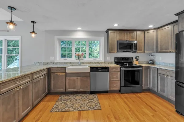 a kitchen with stainless steel appliances granite countertop a stove top oven a sink dishwasher a refrigerator and a microwave oven with wooden floor