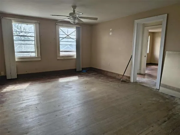 a view of empty room with wooden floor and fan