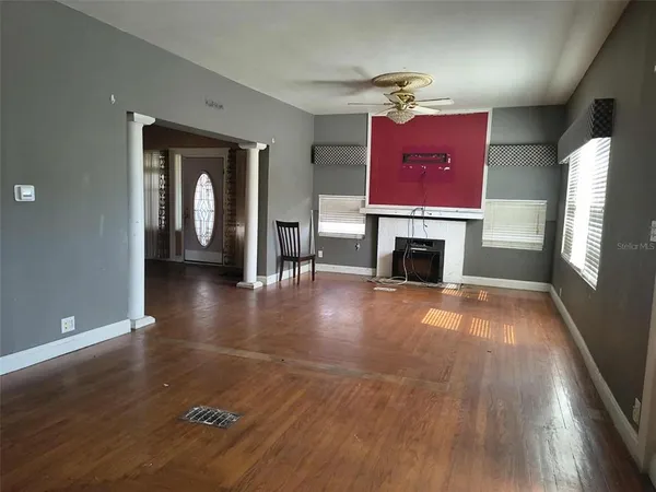 an empty room with wooden floor fireplace and windows