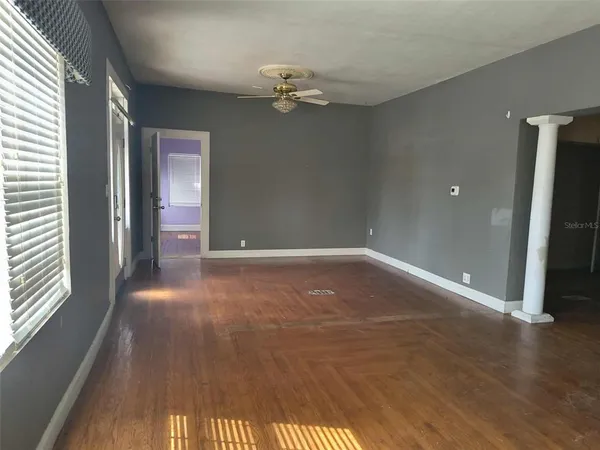 an empty room with wooden floor and windows