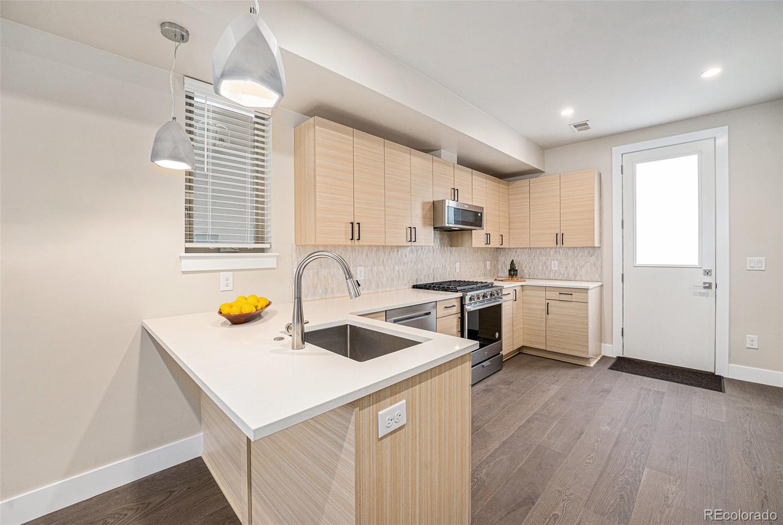 409 Harrison Street, Unit 2 Denver, CO 80206 - Photo 5 of 19 a kitchen with a sink a stove a refrigerator and white cabinets