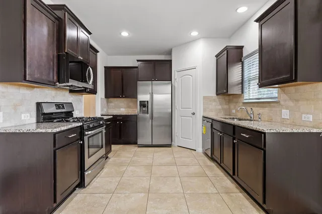 a large kitchen with stainless steel appliances granite countertop a sink stove and refrigerator