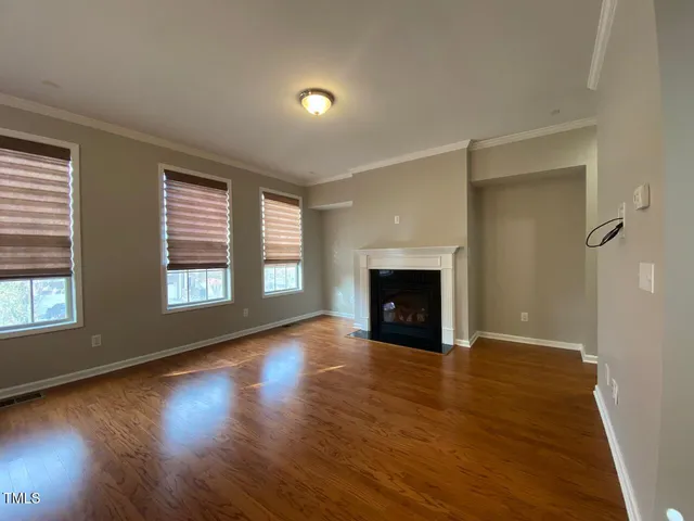 an empty room with wooden floor fireplace and windows