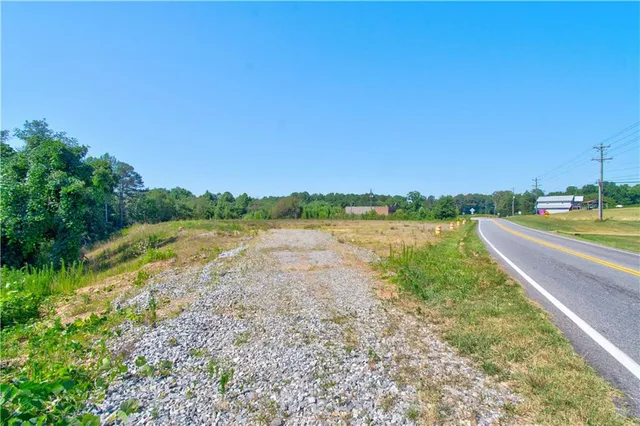 a view of a road with a big yard and large trees