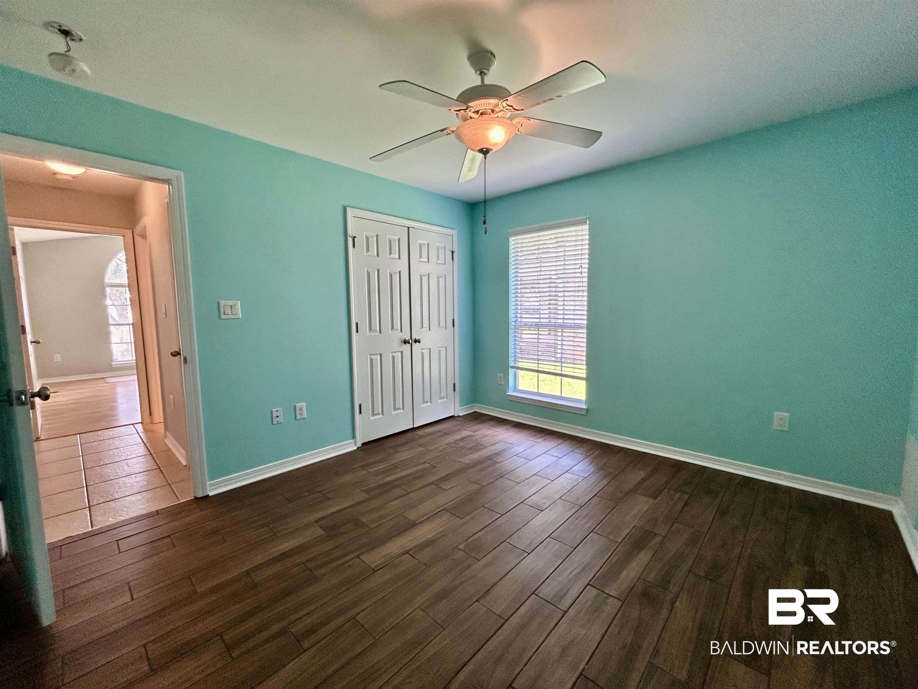 7198 Raintree Lane Gulf Shores, AL 36542 - Photo 24 of 33 Room featuring wood-finish plank flooring, a window with horizontal blinds, and a ceiling fan with integrated lighting