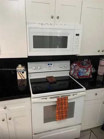 a kitchen with white cabinets and black appliances