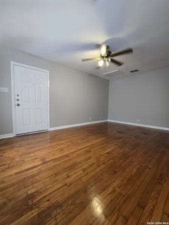 a view of an empty room with a ceiling fan and wooden floor