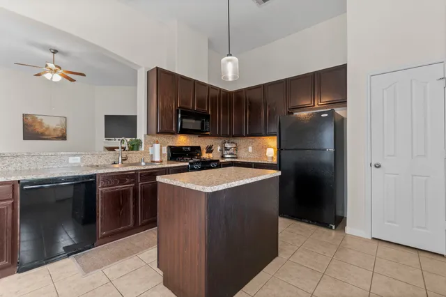 a kitchen with stainless steel appliances granite countertop a refrigerator a sink a stove a microwave and island