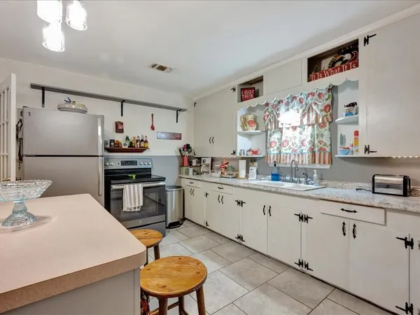 a kitchen with stainless steel appliances a sink a stove a refrigerator cabinets and dining table