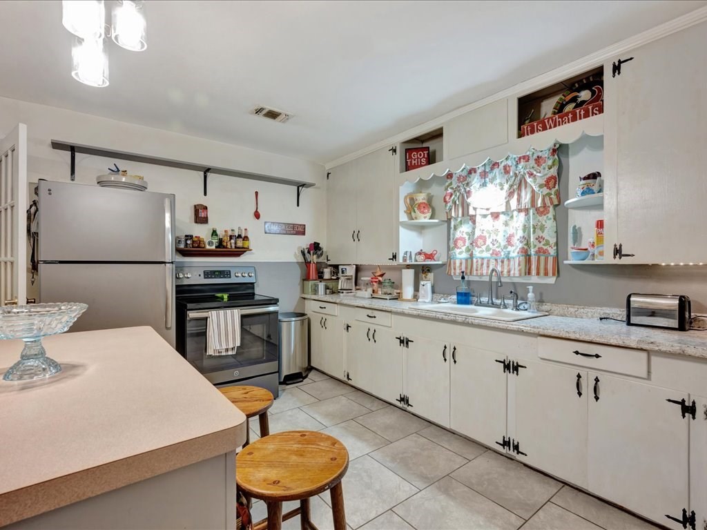 635 Oscar Berry Road Lufkin, TX 75904 - Photo 11 of 36 a kitchen with stainless steel appliances a sink a stove a refrigerator cabinets and dining table