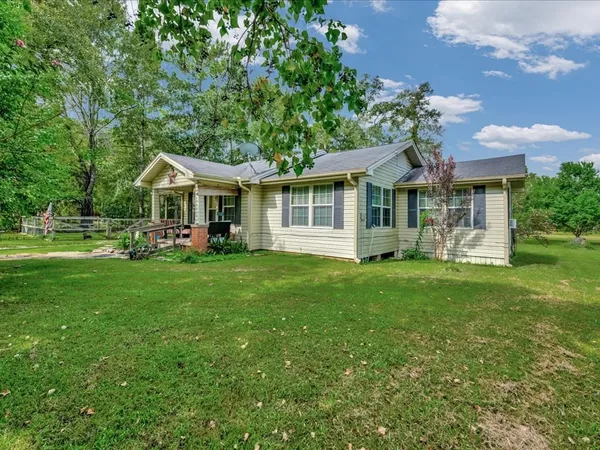 a front view of a house with a garden and trees