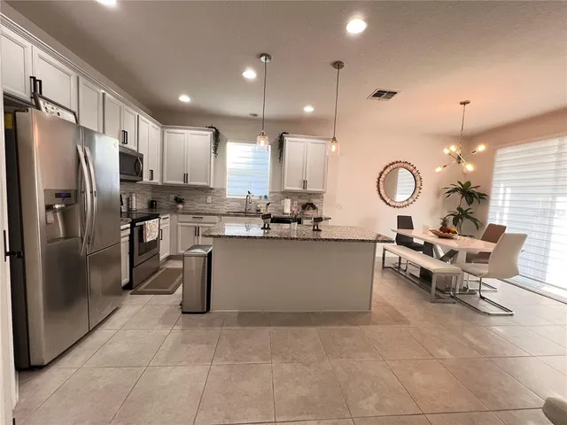 a large kitchen with granite countertop a large counter top stainless steel appliances and cabinets
