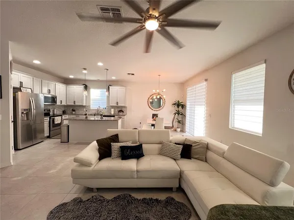a living room with furniture kitchen view and a window