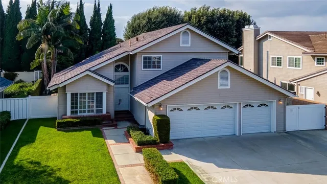 a view of a house with a yard plants and large tree