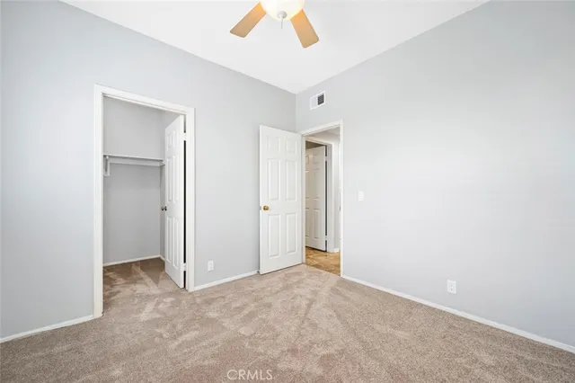 an empty room with a chandelier fan and windows