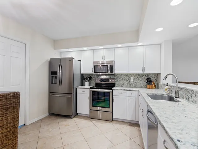 a kitchen with granite countertop a refrigerator and a sink