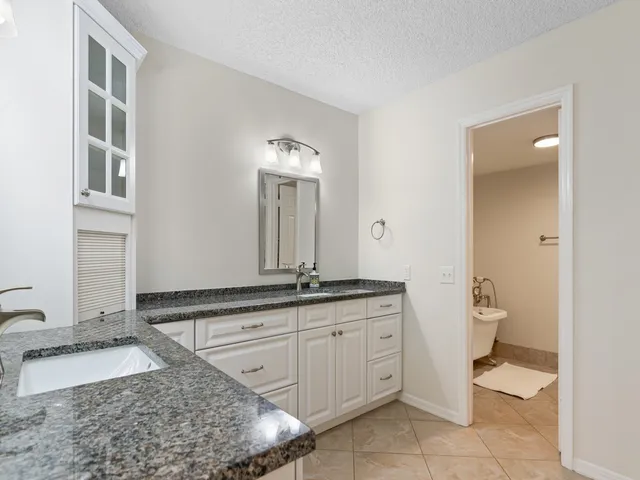 a bathroom with a granite countertop sink and a mirror