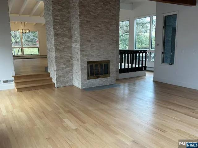 an empty room with wooden floor fireplace and windows