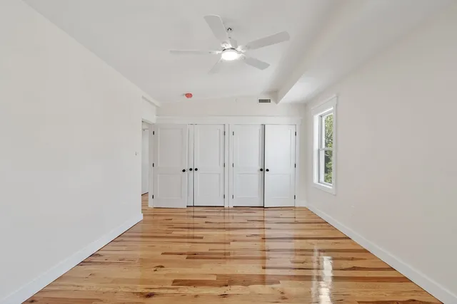 a view of a room with wooden floor and a ceiling fan