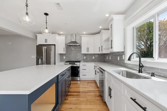 a kitchen with granite countertop a sink a counter top space stainless steel appliances and windows