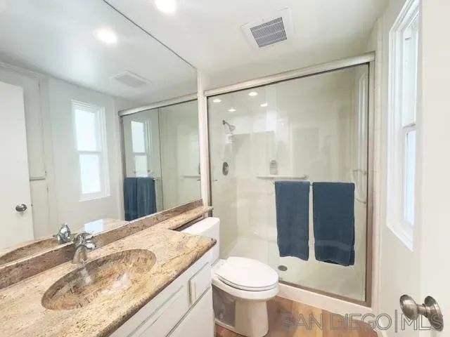 a bathroom with a granite countertop sink toilet and shower