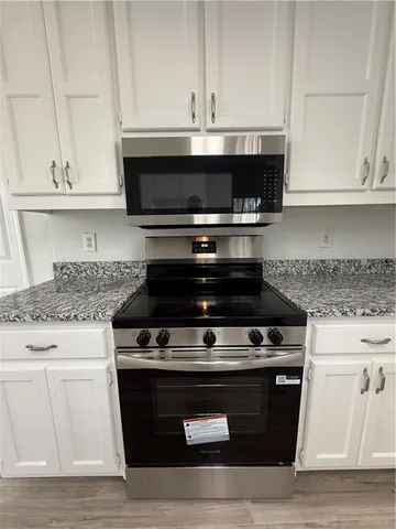 an empty room with wooden floor fireplace cabinet and windows