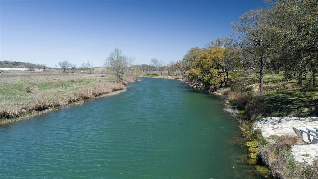 170 Climbing Rock Loop Dripping Springs, TX 78620 - Photo 26 of 30 A tranquil river meanders through a serene landscape with lush trees and open fields under a clear sky.