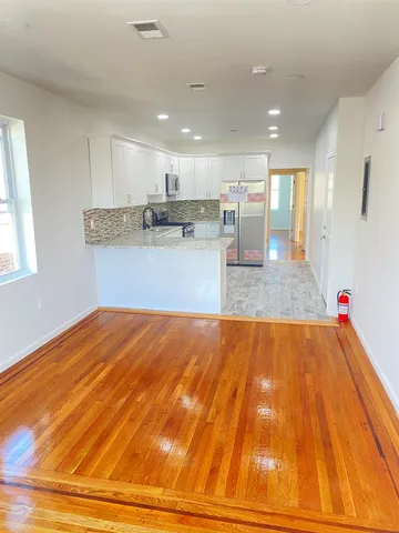 a view of a kitchen with kitchen island a sink wooden floor and a living room view