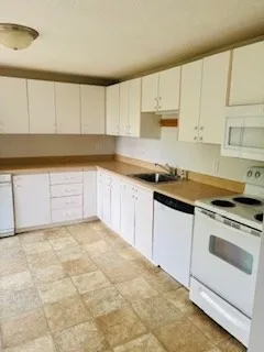 a kitchen with granite countertop white cabinets and white appliances