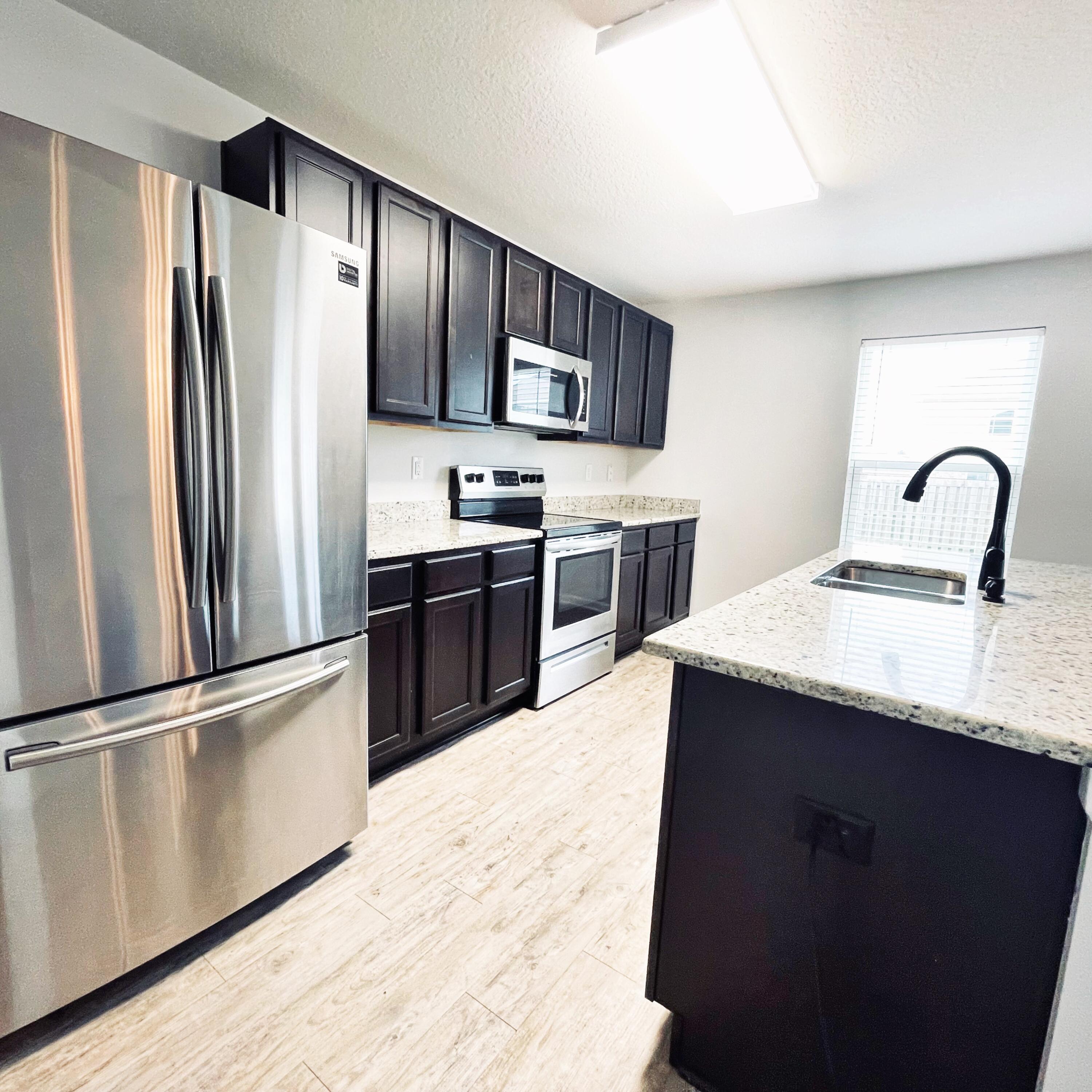 745 Widgeon Way Crestview, FL 32539 - Photo 4 of 17 a kitchen with stainless steel appliances granite countertop a refrigerator a sink and a stove