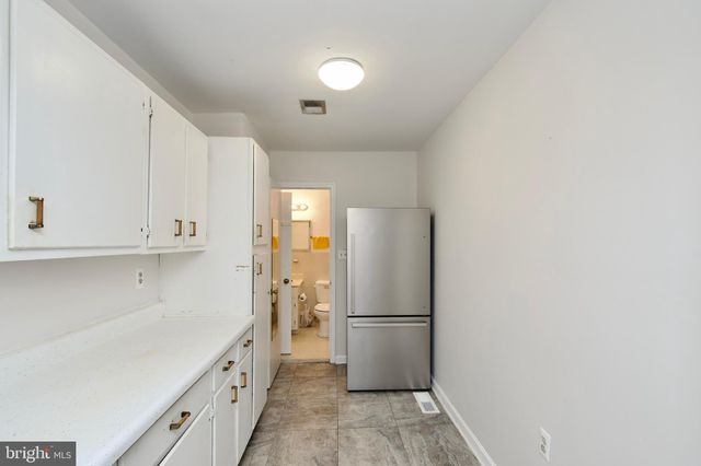 a view of a kitchen with white cabinets and a refrigerator