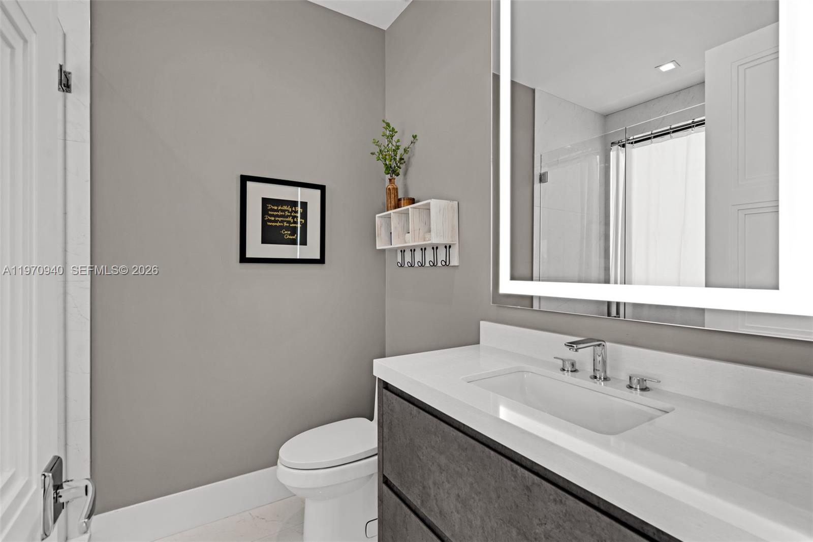 225 Northeast 3rd Street Boca Raton, FL 33432 - Photo 27 of 36 a bathroom with a granite countertop sink a toilet and a mirror