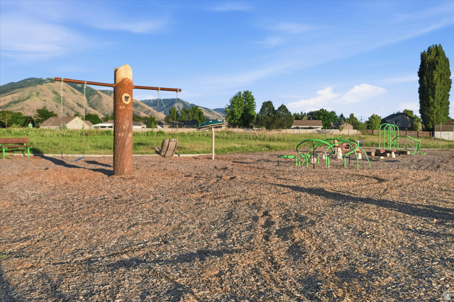 2257 South 1090 West, Unit 74 Nibley, UT 84321 - Photo 29 of 40 Outdoor playground featuring a swing set with a wood-look support post, green-framed climbing structures, and a wood chip ground cover