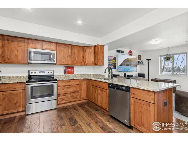 a kitchen with granite countertop a stove top oven a sink dishwasher and cabinets with wooden floor