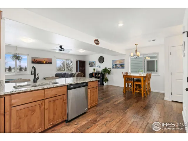 a kitchen with stainless steel appliances granite countertop a sink dishwasher a stove a dining table and chairs with wooden floor